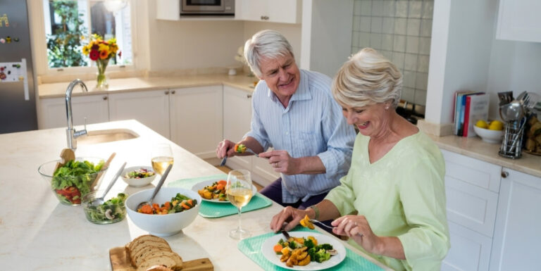 Elderly Couple Enjoying a Healthy Vegetable Meal Together in Their Kitchen at Independent Living Facility